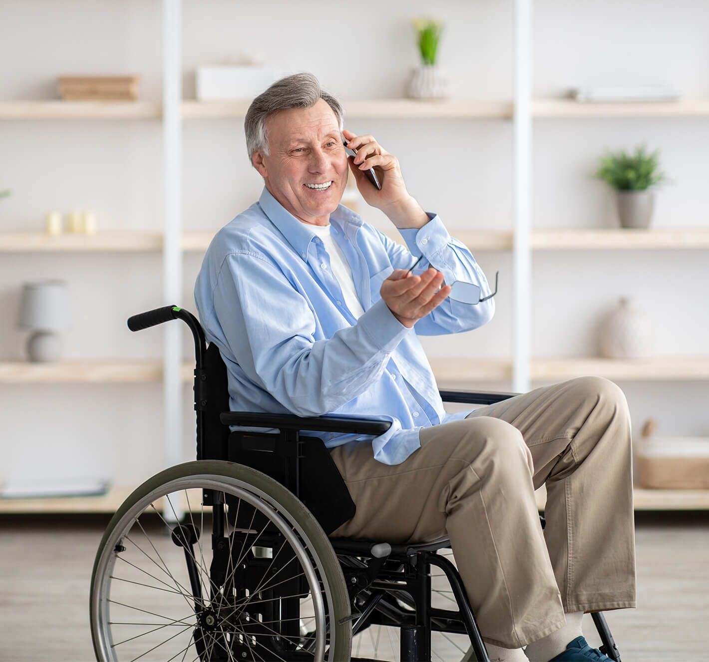 Happy old man in a wheelchair ordering medical supplies over the phone 